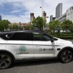 Close-up of a Baidu Apollo Go robotaxi, showing the side of the autonomous vehicle on a road