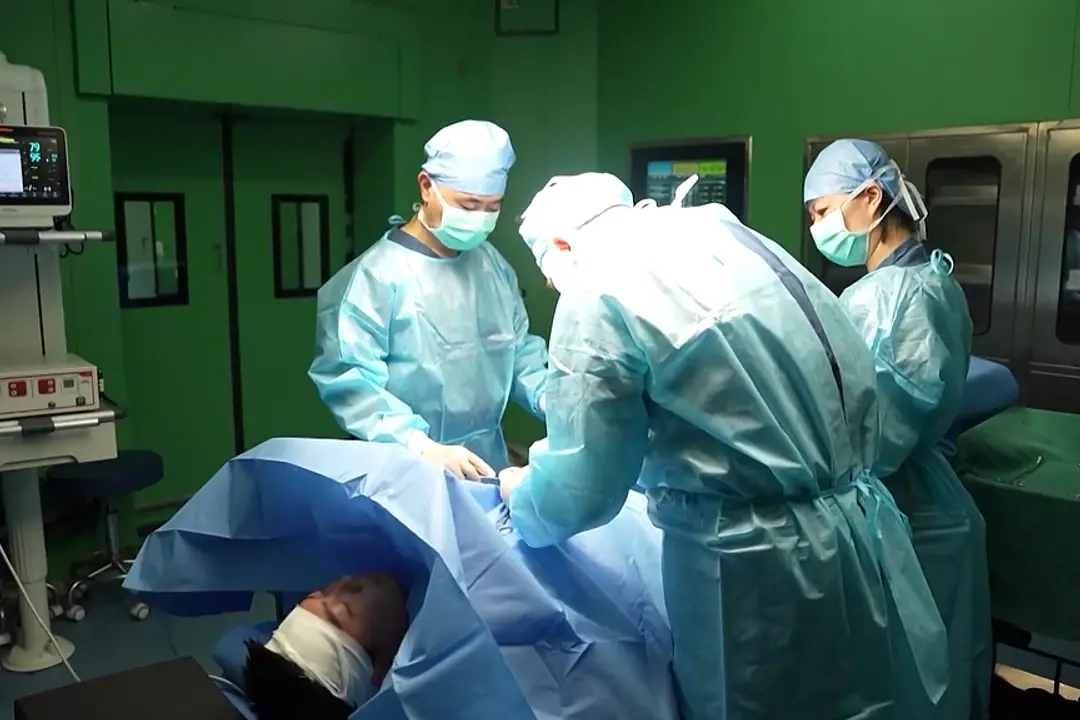 Photograph of a hospital operating theatre with surgeons operating on a patient