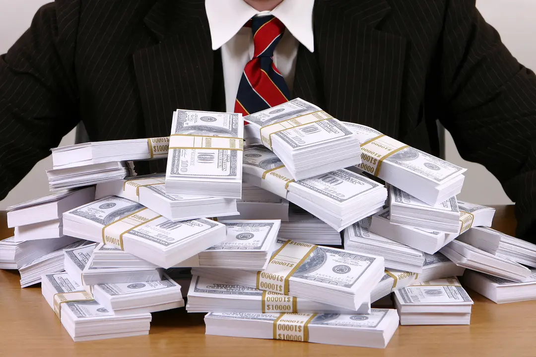 photograph shows wads of cash with a suited man in the background