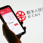 photograph shows a smartphone with the e-CNY app with a logo in the background