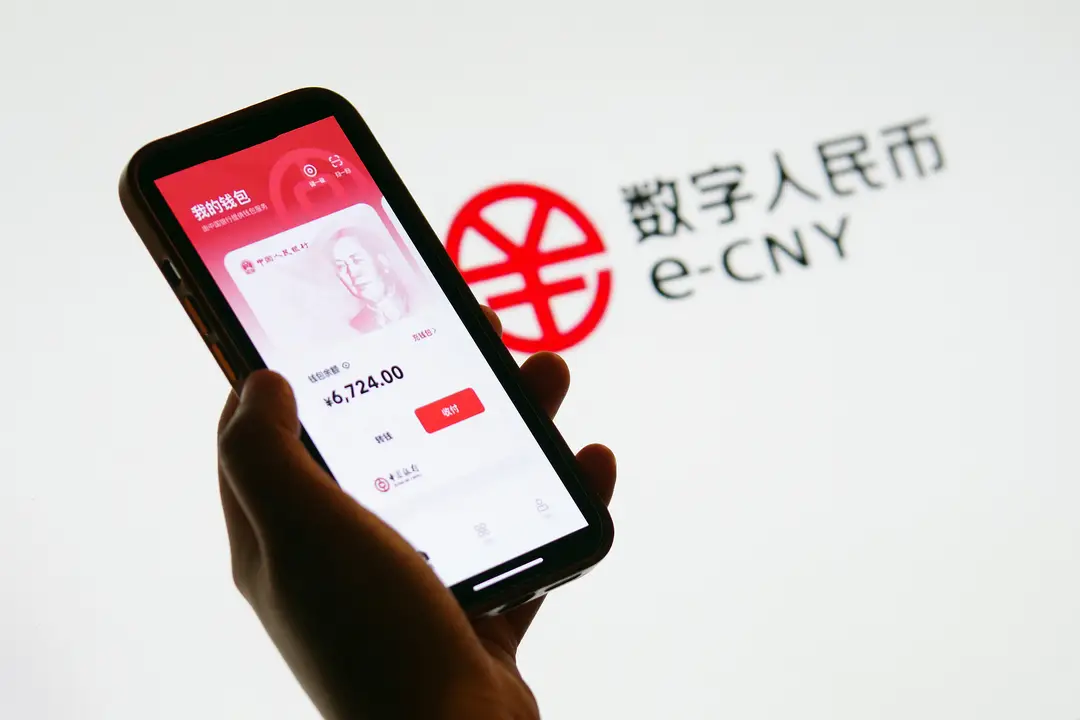 photograph shows a smartphone with the e-CNY app with a logo in the background