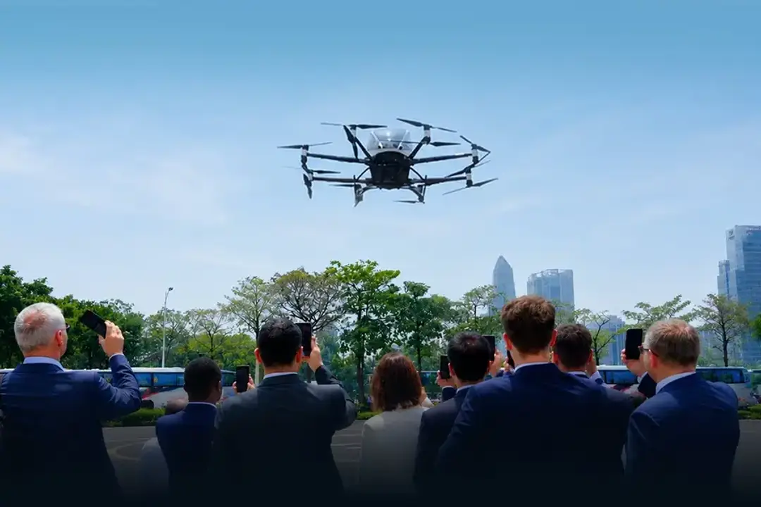 Photograph shows a crowd watching a demonstration of an eVTOL vehicle flight