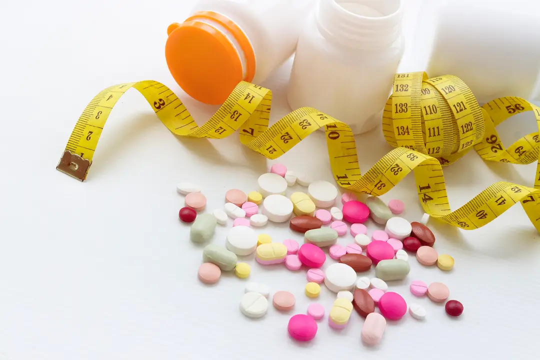 Photograph shows a range of weight-loss pills in the foreground with a measuring tape in the background